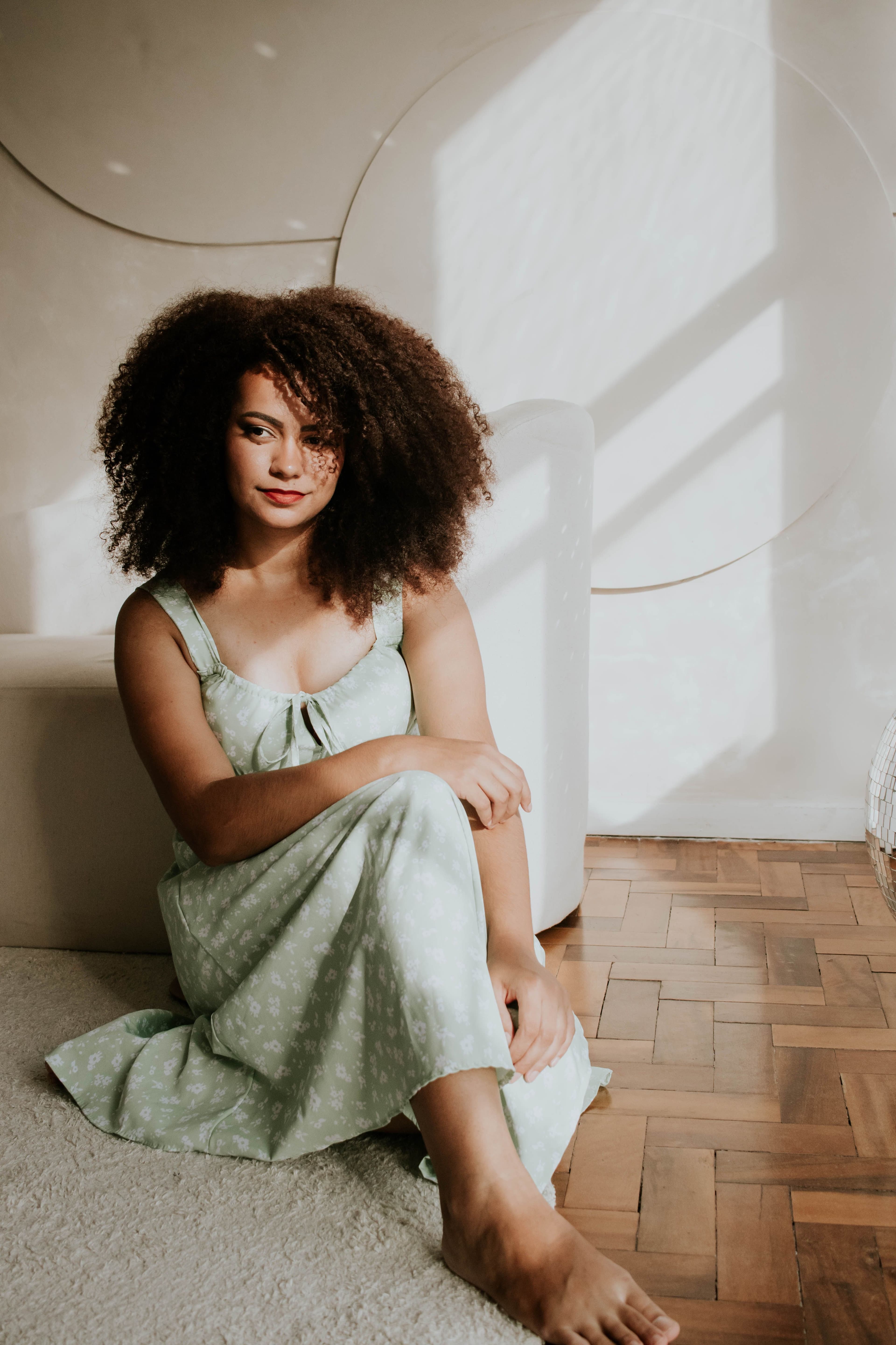 A woman in a soft green dress seated in warm natural light